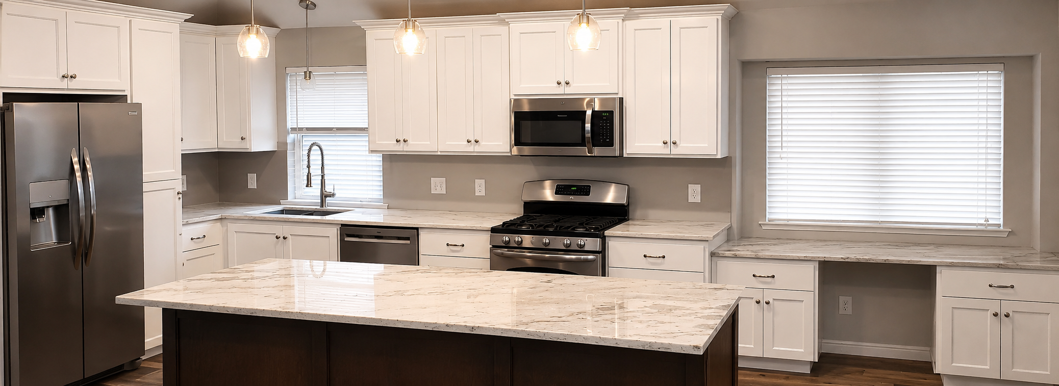 Custom kitchen remodel featuring white shaker cabinets, a large quartz island, stainless steel appliances, built-in desk area, and modern pendant lighting by Mason's Quality Construction